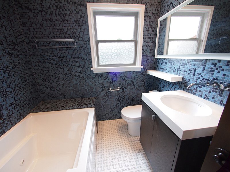 The bathroom with jacuzzi tube and glass tile walls